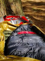A Criterion Ultralight 350 sleeping bag in a wild camp photoshoot with a tree in the background